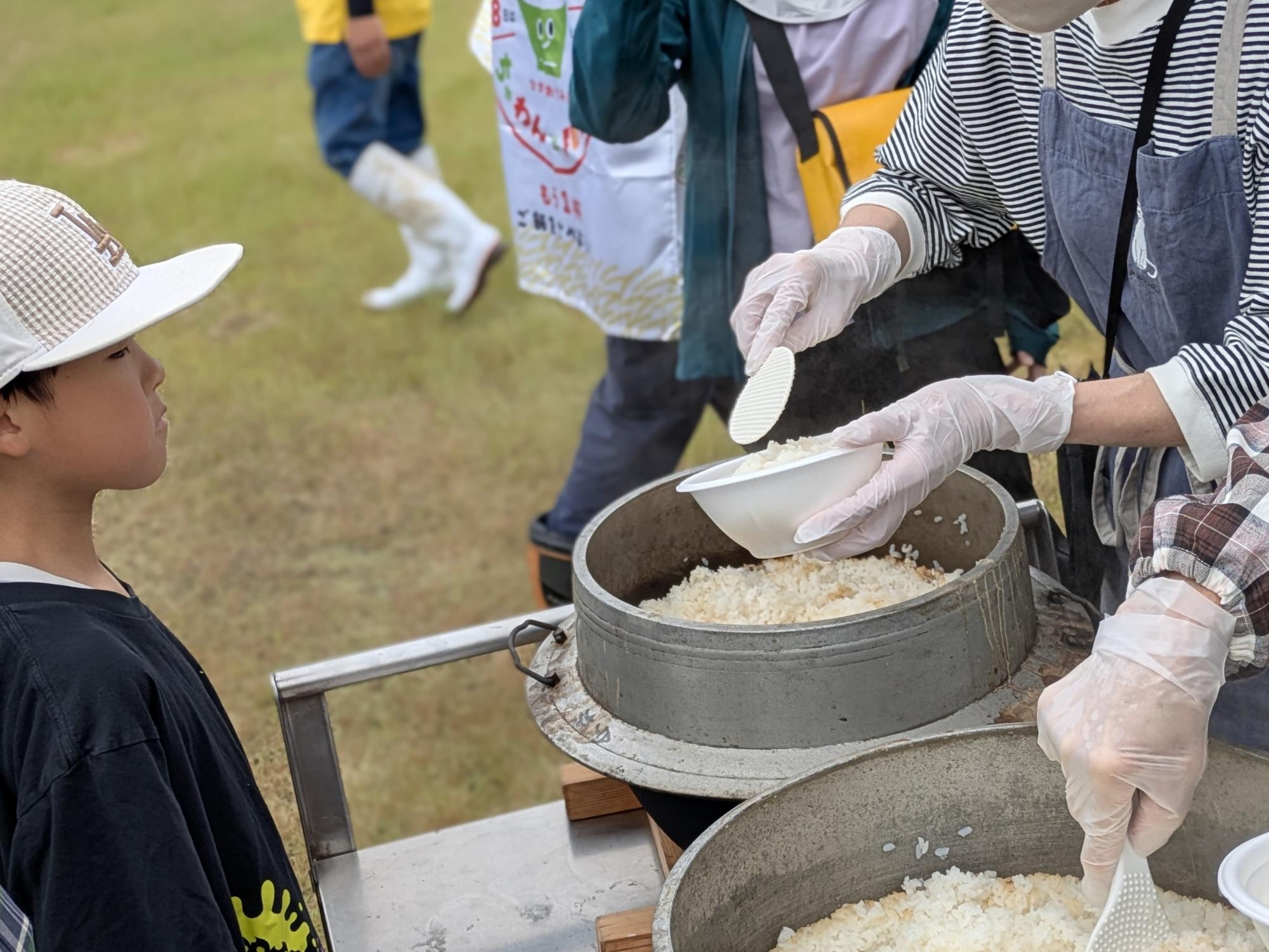 釜で炊いたお米を見る男の子